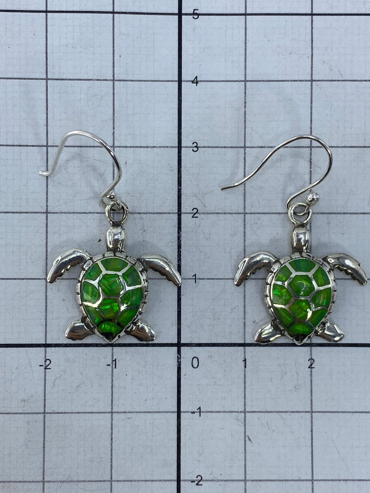 Aretes de plata de tortuga marina sobre fondo azul, listos para regalar