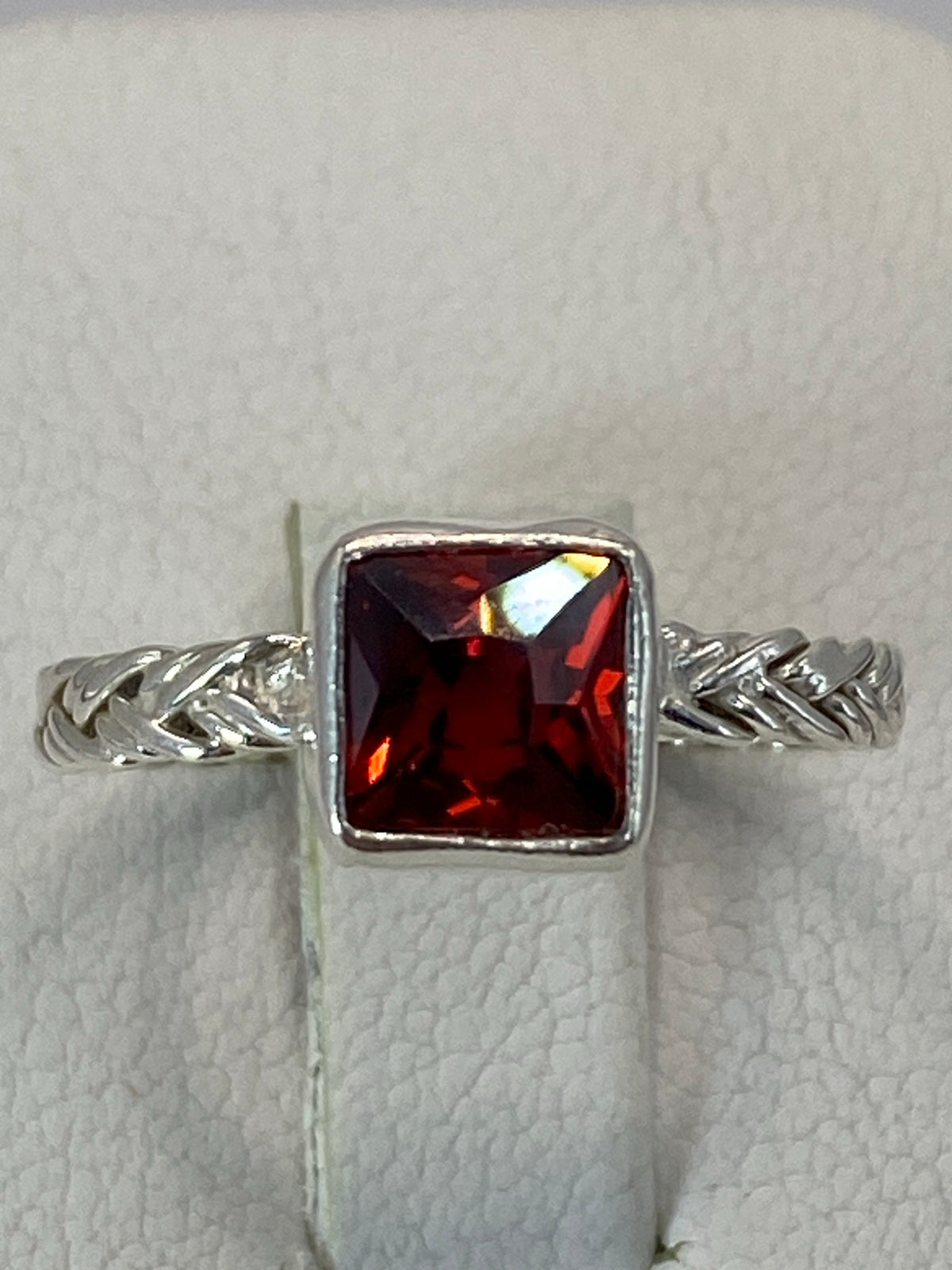 Anillo de plata 925 con circonia roja en bisel, vista frontal sobre blanco