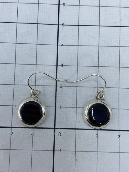 Par de aretes colgando, mostrando el tamaño de 2.5 cm y la transparencia del ópalo