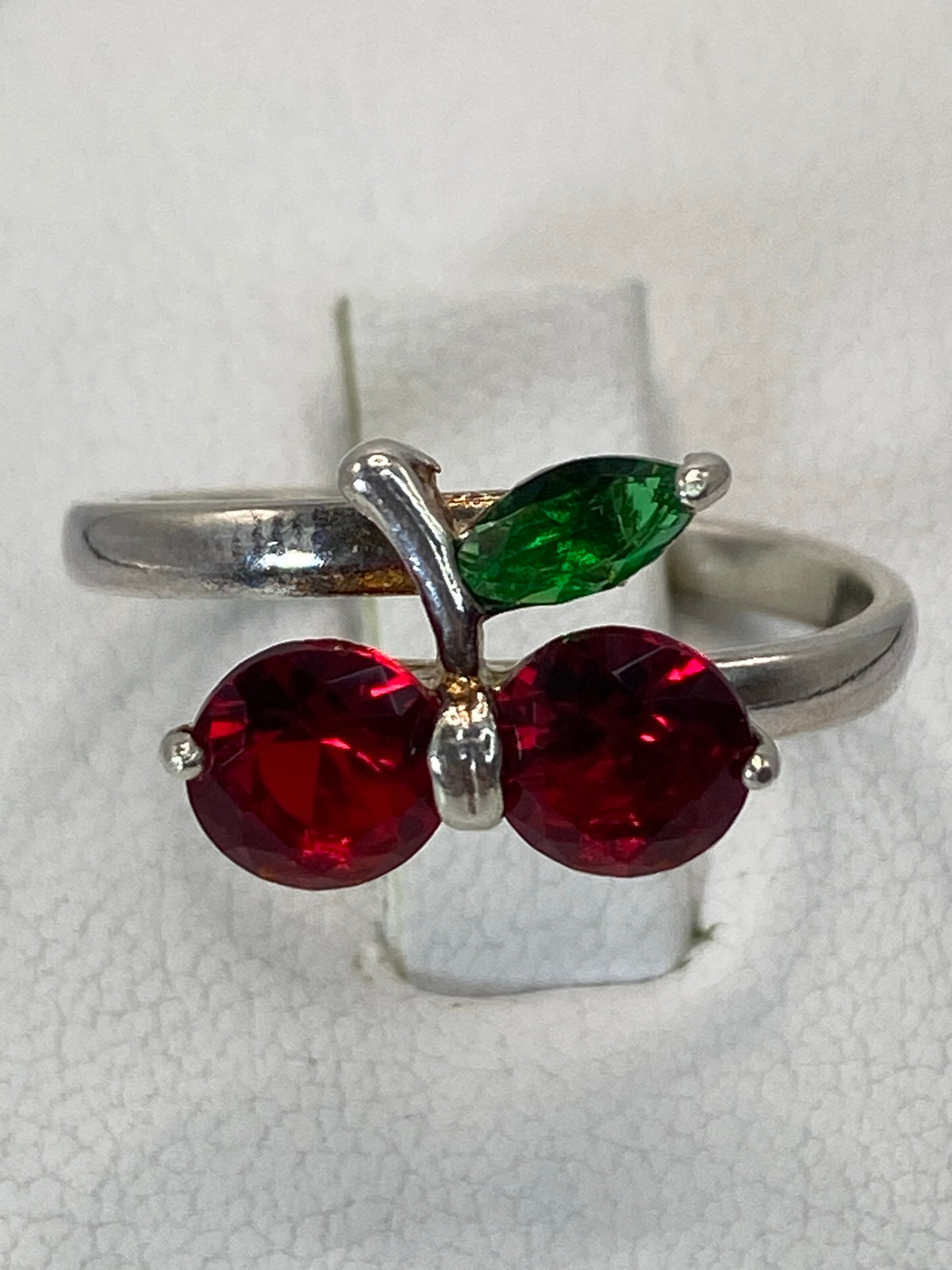 Anillo de plata solitario con circonia roja facetada en la mano de una mujer