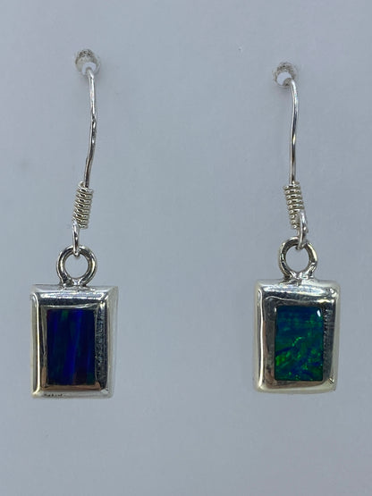 Aretes de plata con ópalo de fuego multicolor en tonos naranjas y verdes colgando en par