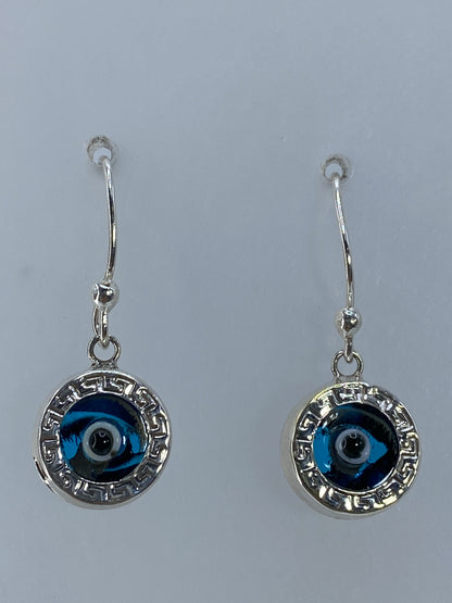 Aretes de plata con ojo azul y marco geométrico de Taxco, fotografiados frente a fondo blanco
