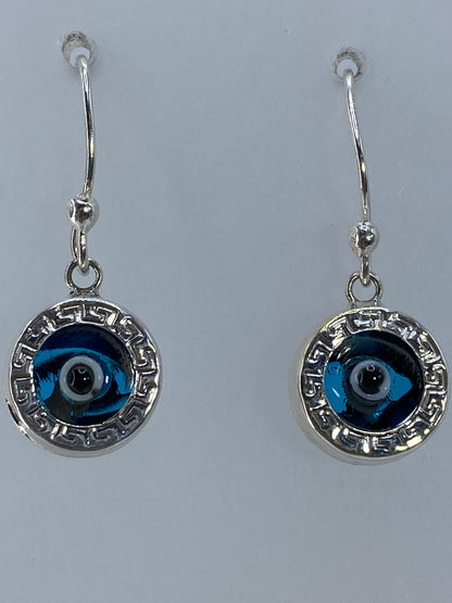 Par de aretes colgando de ganchos plateados, mostrando el diseño circular con greca