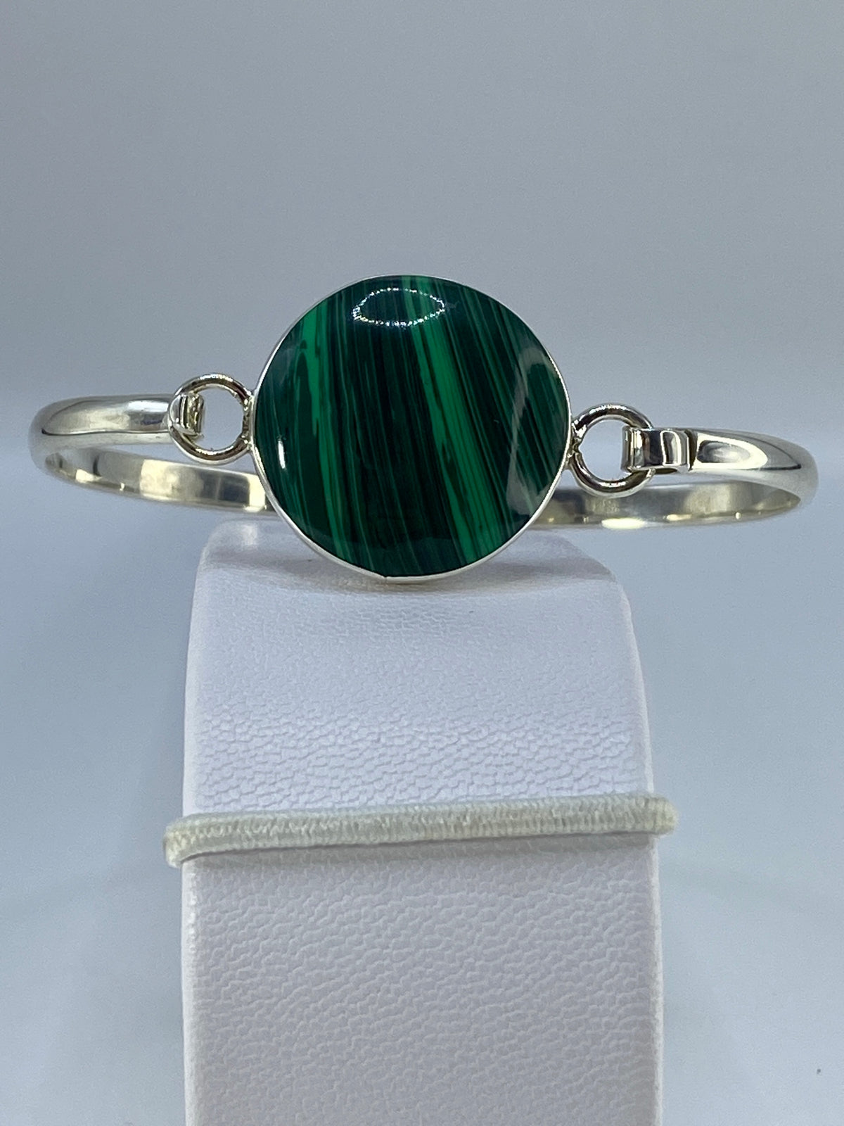 Brazalete rígido de plata 950 con malaquita verde sobre soporte de lino