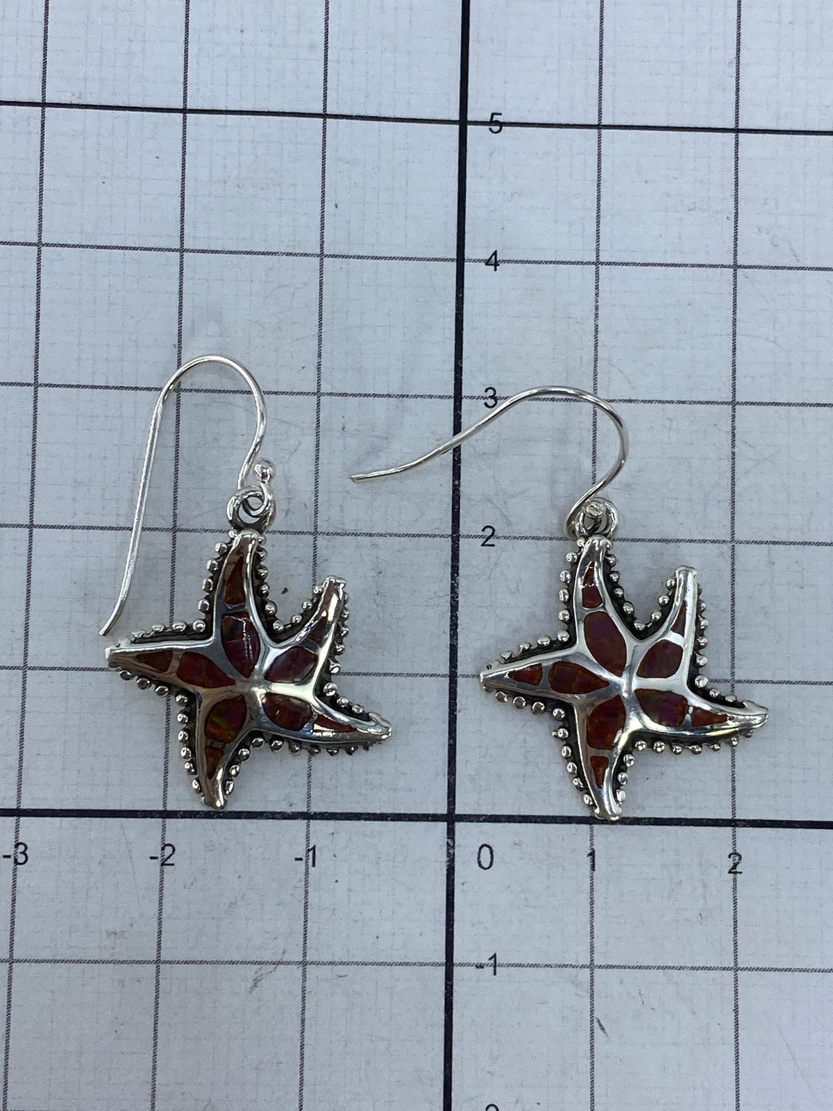 Aretes sobre cuadrícula de medición mostrando largo de 3 cm