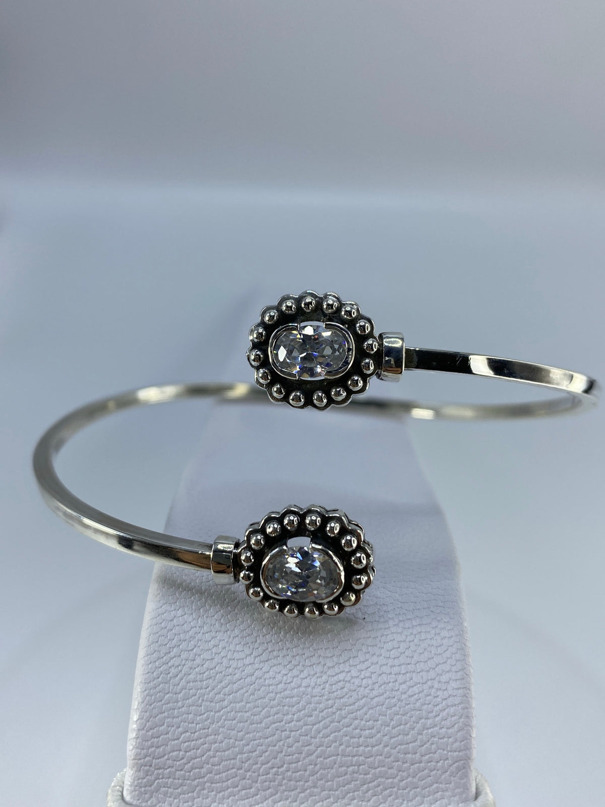Brazalete rígido de plata 925 con circonia engastada en patrón floral, visto de frente