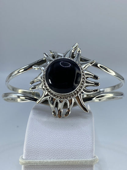 Brazalete rígido de plata con ónix negro pulido engastado a mano, en muñeca de mujer