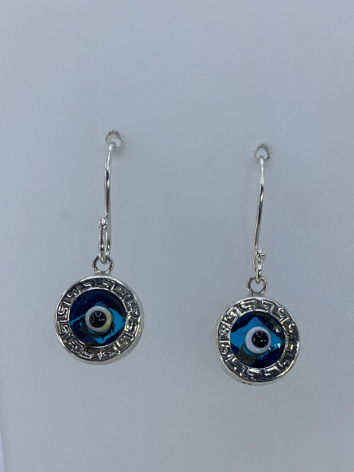 Detalle frontal de un arete mostrando la incrustación de piedra azul y el diseño de grecas