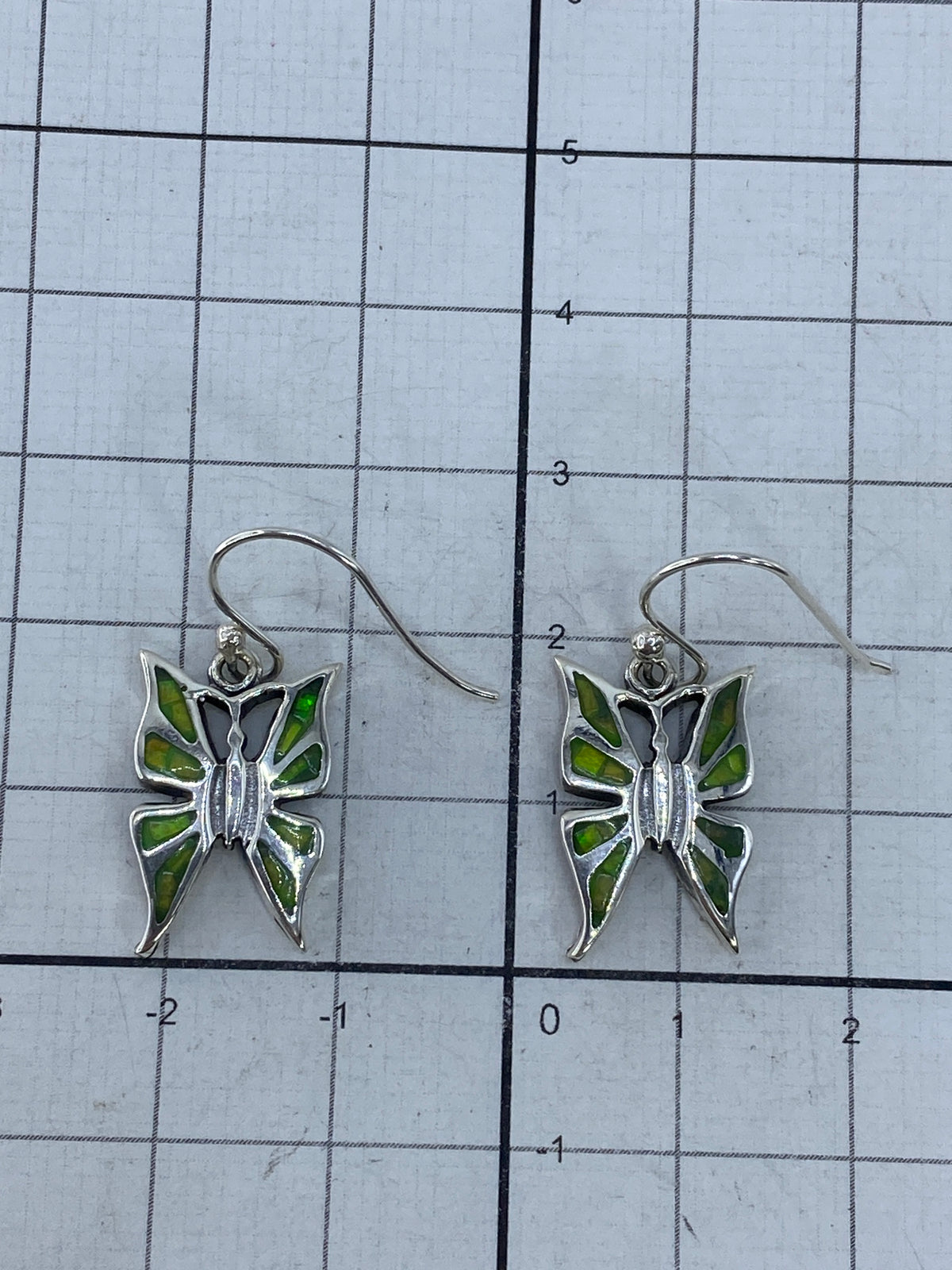 Aretes de ópalo de fuego sobre fondo blanco mostrando el brillo natural de la piedra