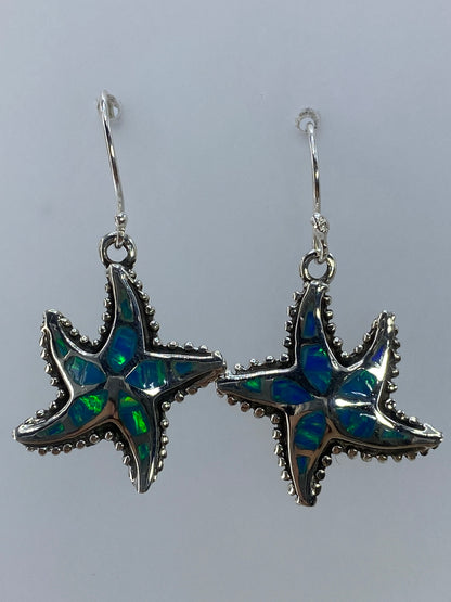 Aretes en par de plata con ópalo de fuego verde olivo, colgando sobre fondo gris neutro