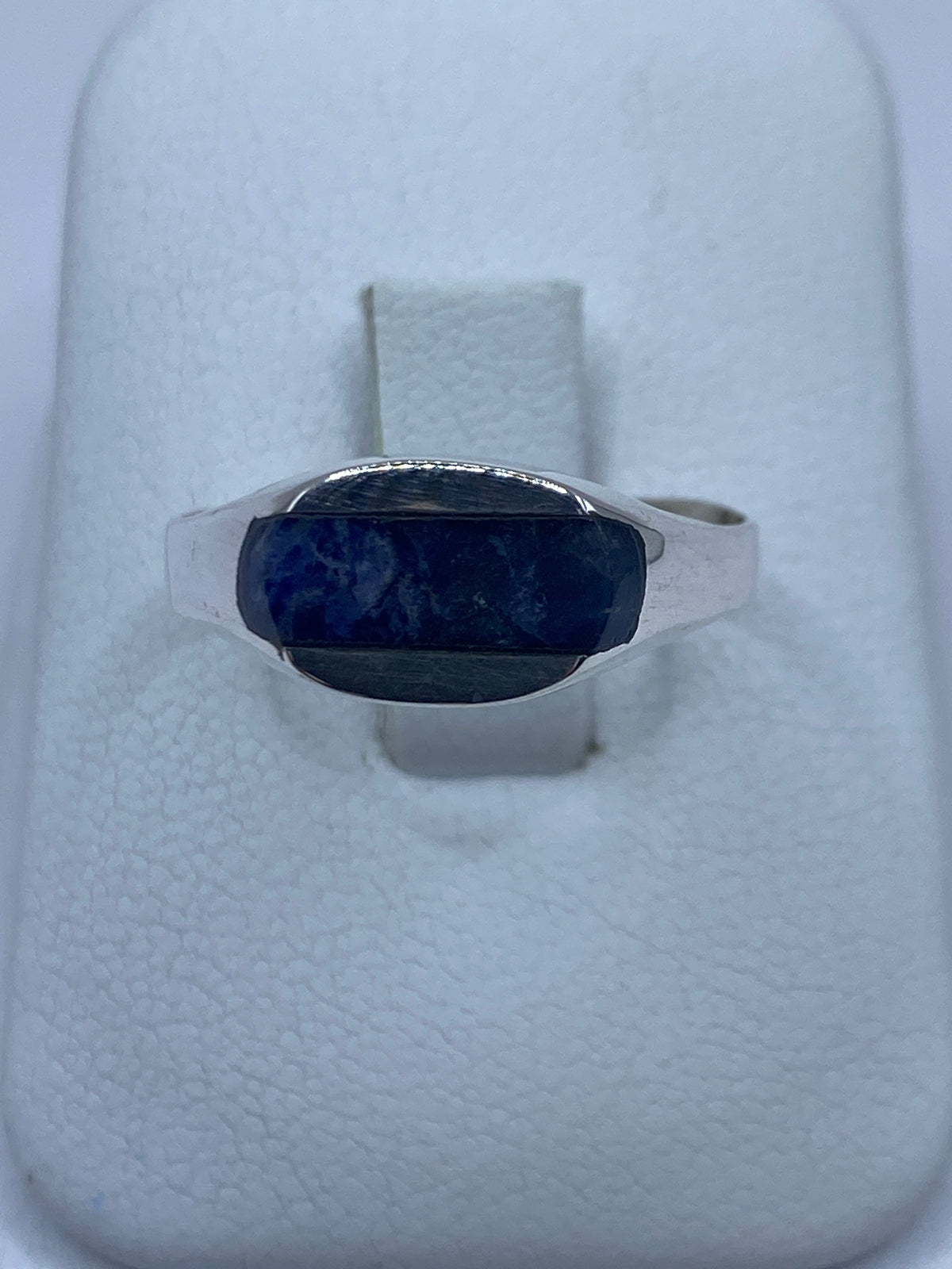 Anillo de plata con lapislázuli azul en la mano, mostrando el solitario engastado