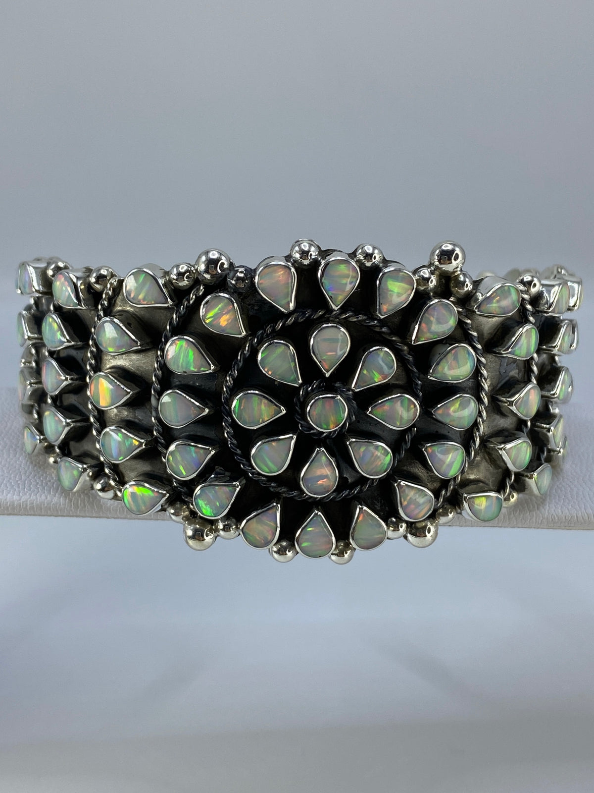 Brazalete de plata 950 con ópalo de fuego multicolor engastado, vista frontal sobre fondo gris