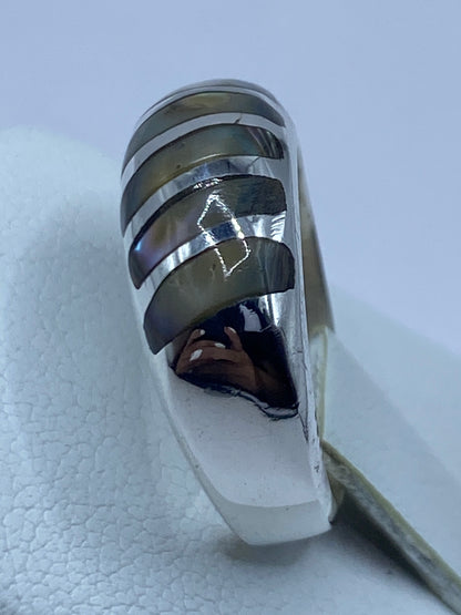 Anillo puesto en dedo mostrando el brillo iridiscente de la concha
