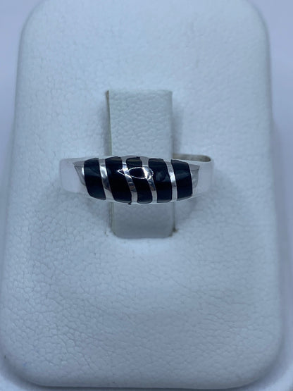 Anillo de plata con ónix negro en mano, mostrando el engaste minimalista