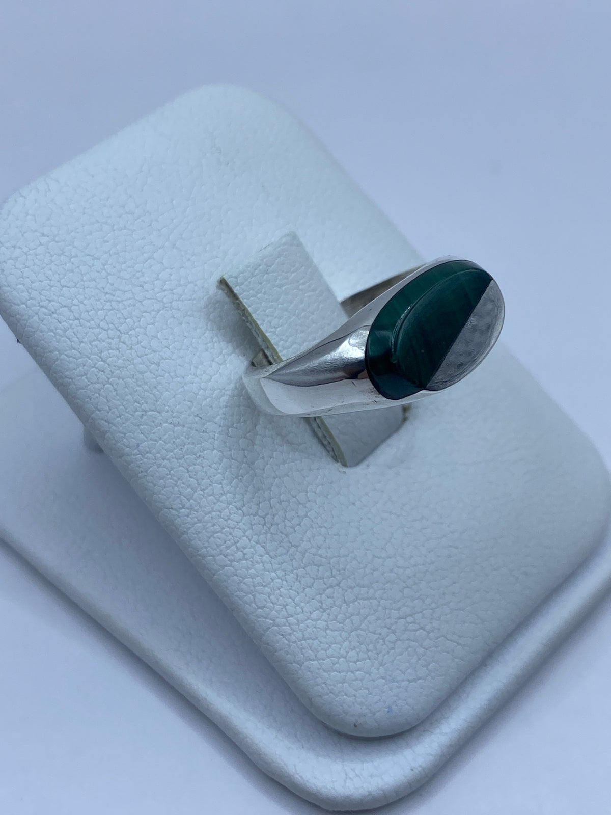 Anillo en malaquita verde sobre dedo, mostrando el pulido de la plata y la piedra natural