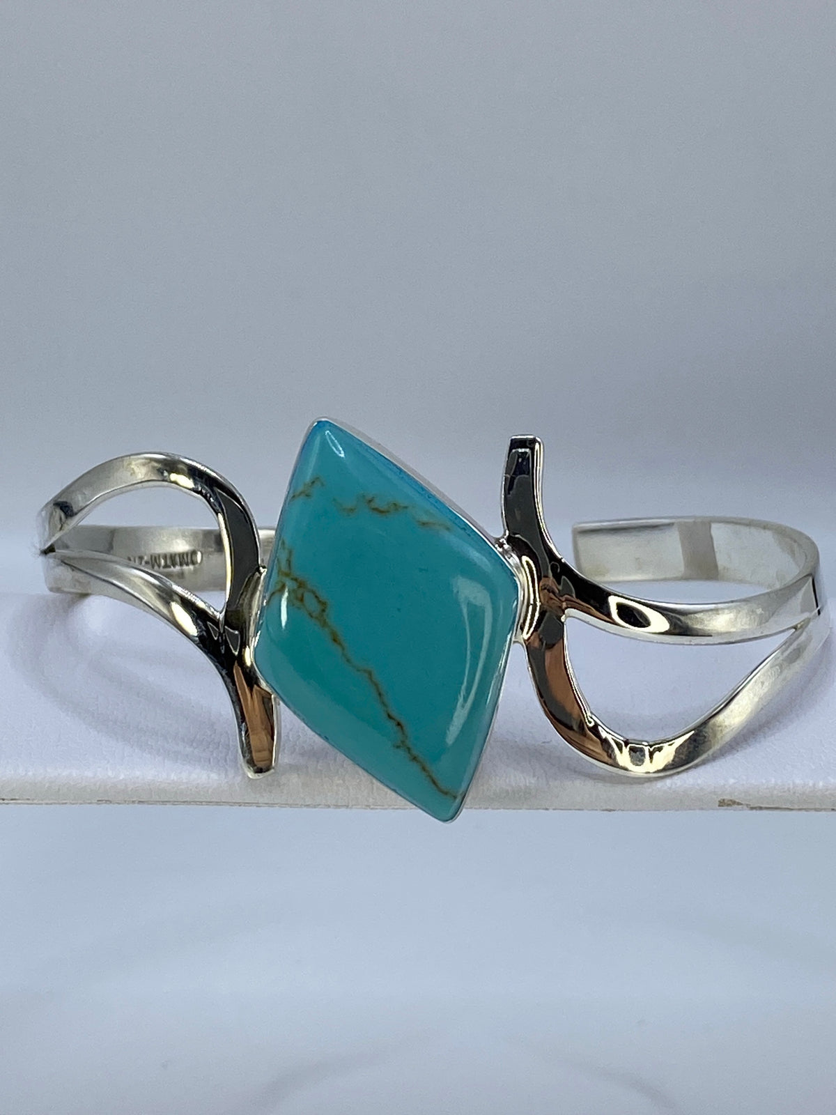 Brazalete de plata 925 con turquesa azul abierto sobre tela blanca