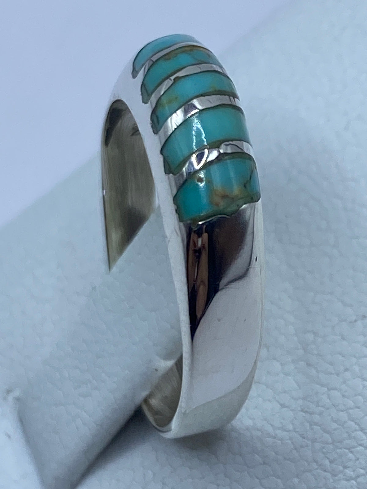 Detalle lateral del anillo con bandas de plata pulida y turquesa