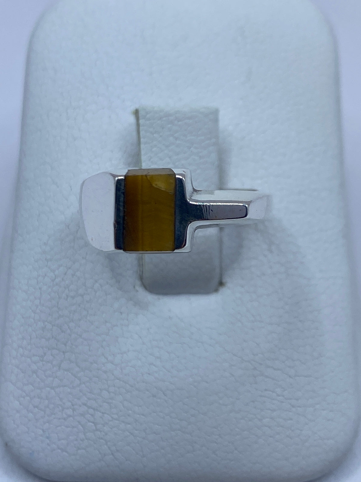 Anillo de plata con Ojo de Tigre café en la mano, mostrando el brillo felino de la piedra