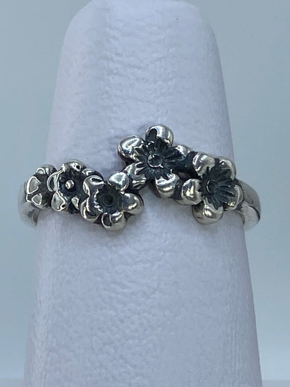 Anillo de plata con flores puesto en la mano, mostrando el acabado pulido y brillante