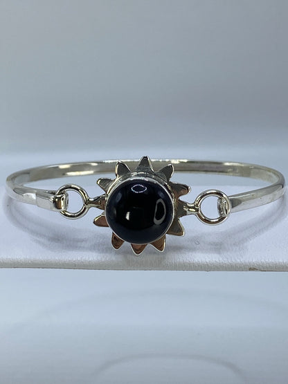 Brazalete rígido de plata con ónix negro engastado, visto de frente sobre fondo blanco