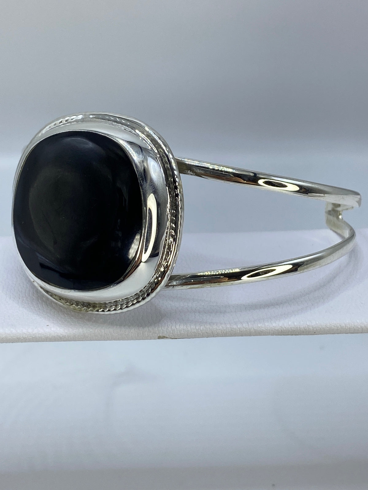 Brazalete rígido de plata en ónix negro visto desde el lado, destacando el ancho de la banda