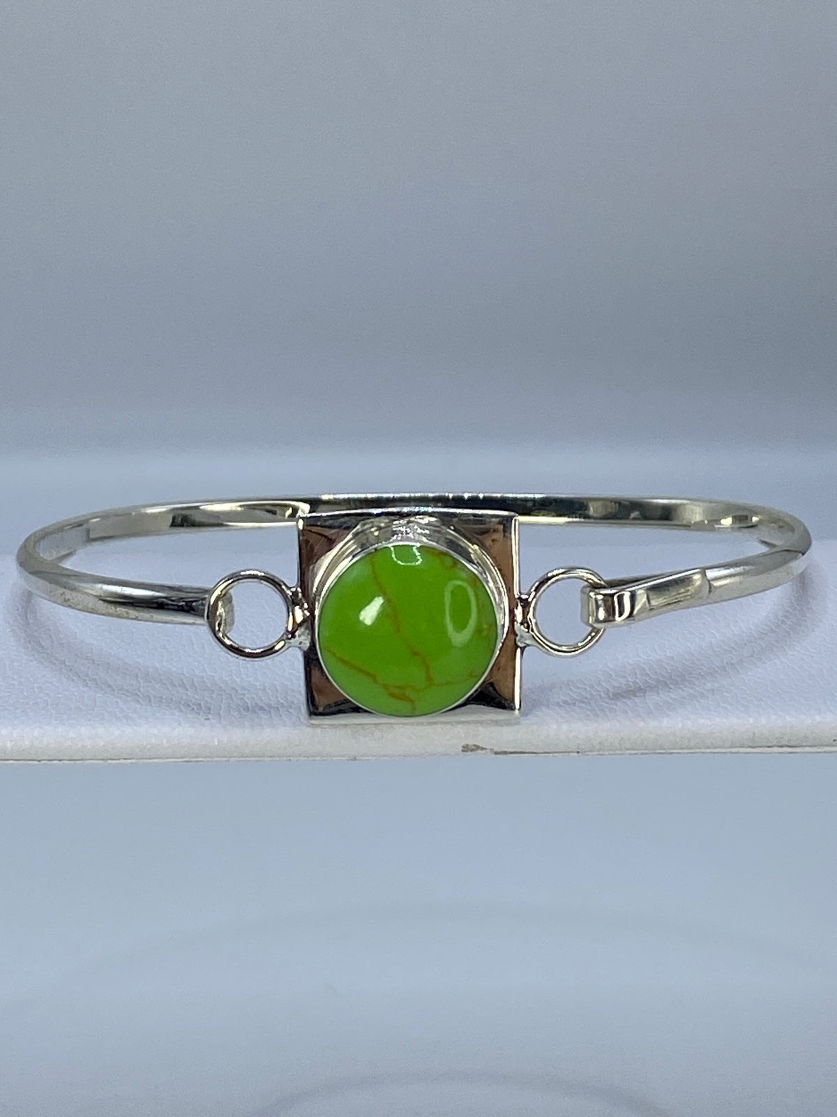 Brazalete de plata rígido con turquesa verde engastada, vista superior en muñeca
