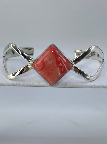 Brazalete de plata 925 con coral rosa engastado, visto de frente sobre fondo gris