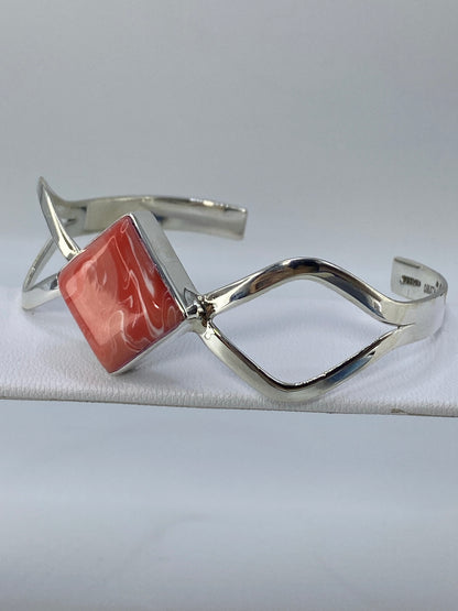 Brazalete tipo esclava en plata con coral rosa puesto en la muñeca