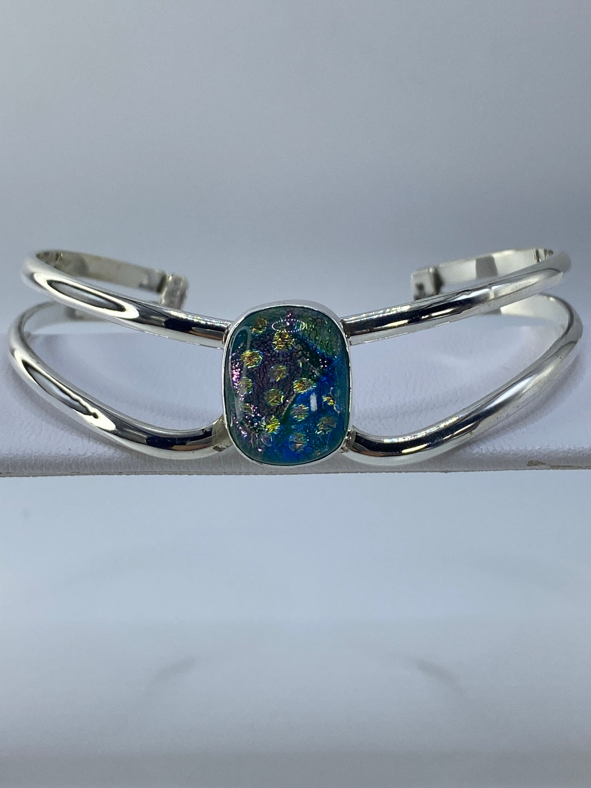 Brazalete rígido de plata con piedra multicolor engastada, visto desde arriba