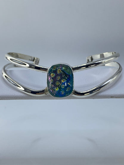 Brazalete rígido de plata con piedra multicolor engastada, visto desde arriba
