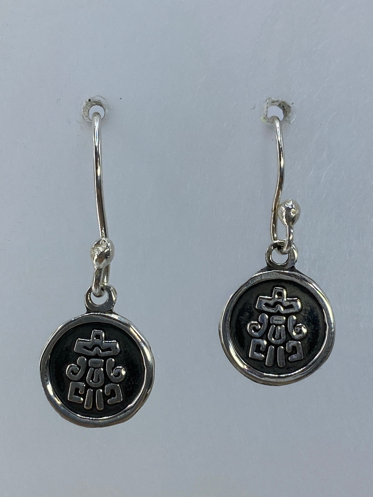 Par de aretes de plata con cruz religiosa repujada, colgando de ganchos de plata
