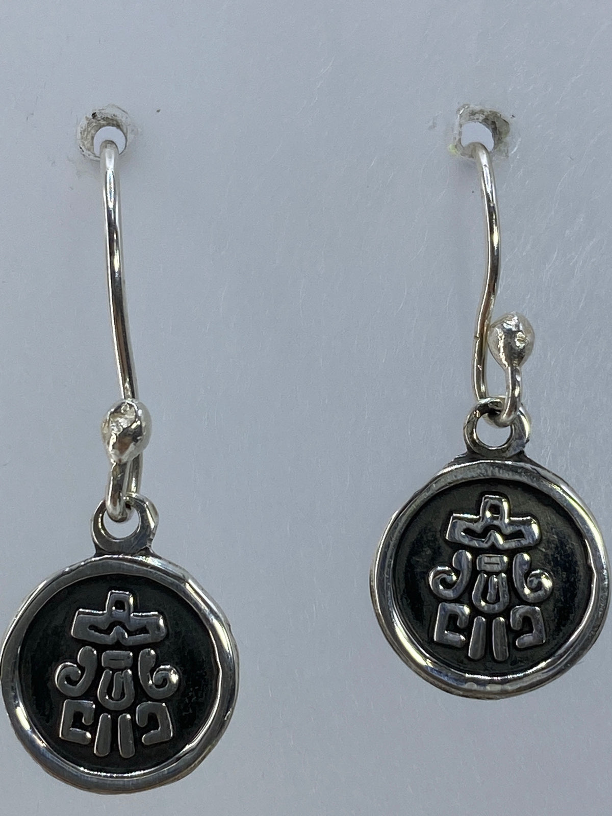 Aretes religiosos de 2.5 cm de largo sobre fondo neutro