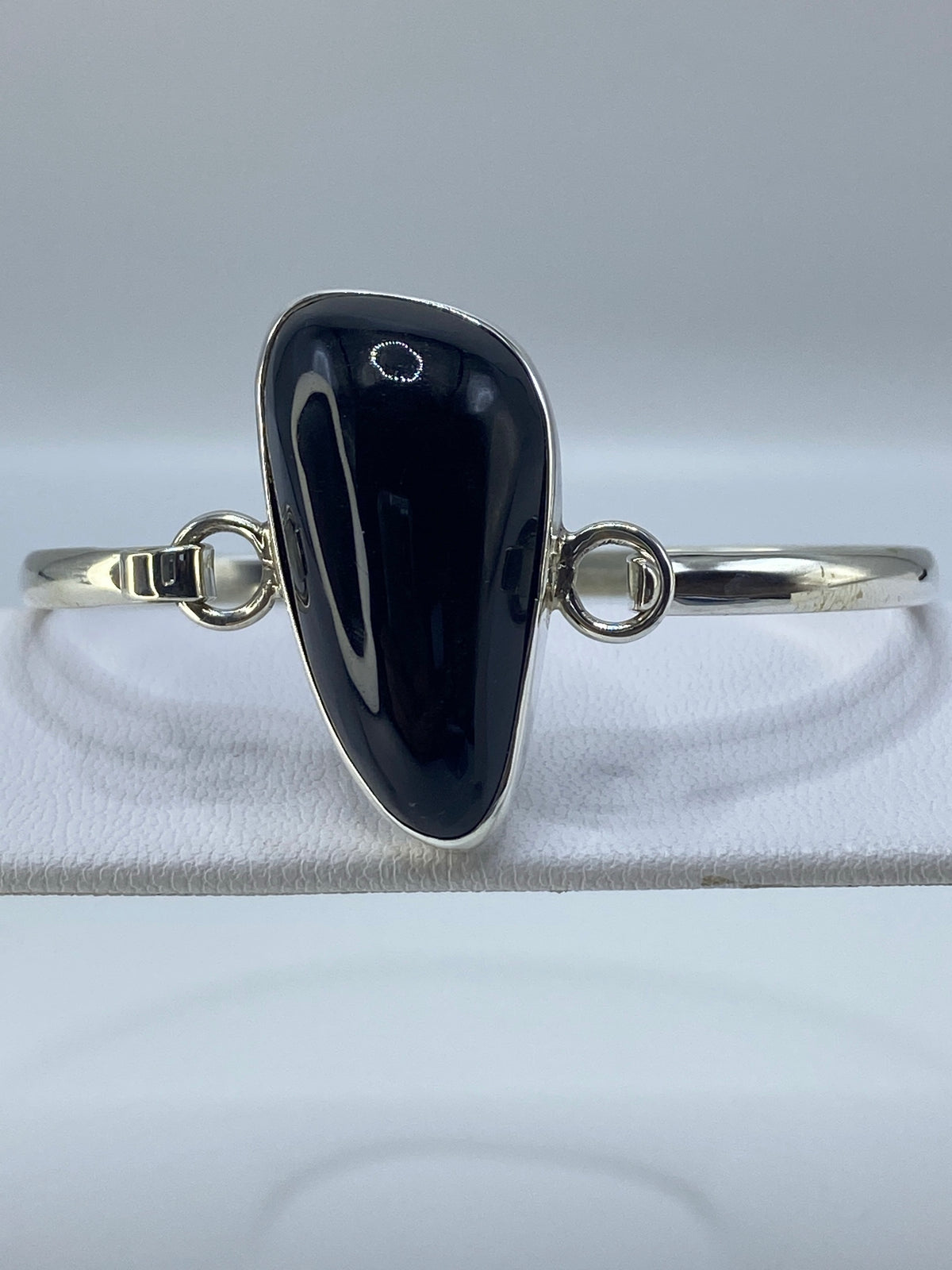 Brazalete de plata 950 con ónix negro engastado, vista frontal sobre tela blanca
