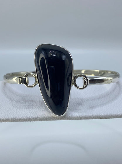 Brazalete rígido tipo esclava de plata pura con ónix brillante puesto en la muñeca