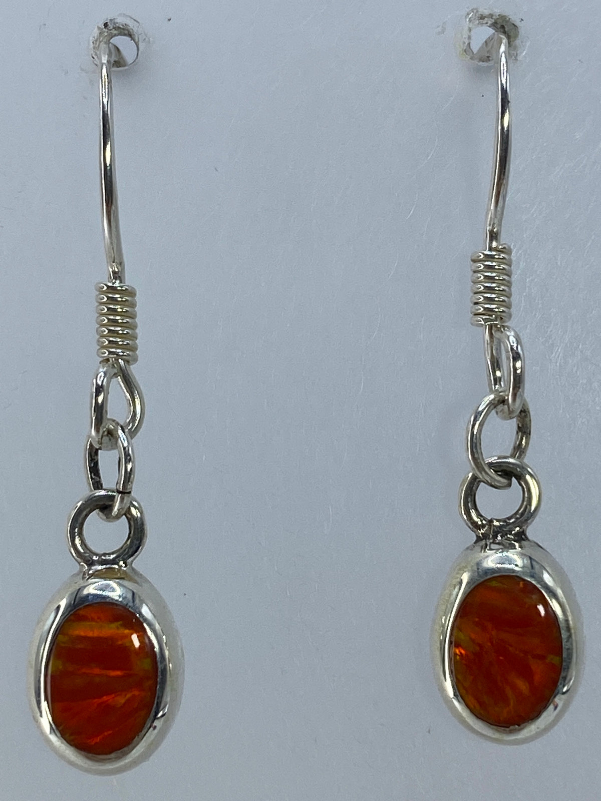 Aretes colgando de un hilo, mostrando los 3 cm de largo y el color naranja intenso