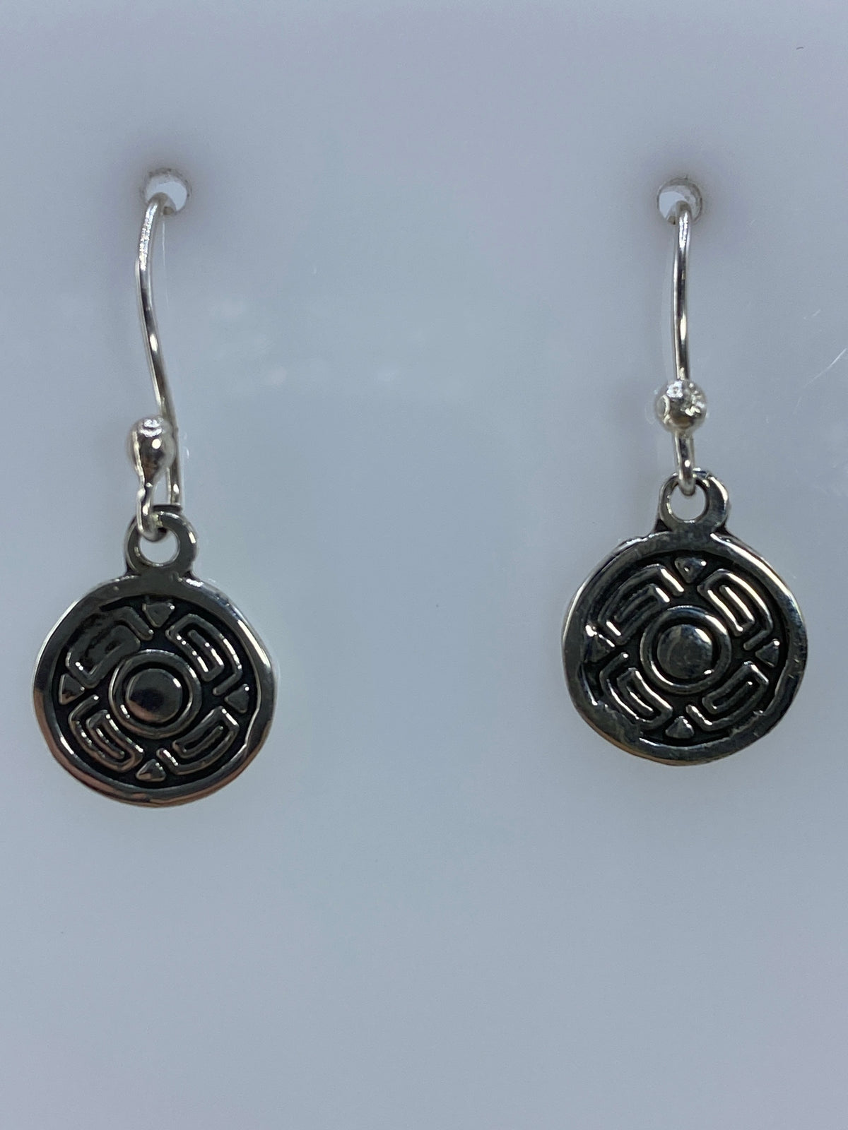 Aretes de plata repujado con motivo prehispánico circular, 2.2 cm, colgando del gancho
