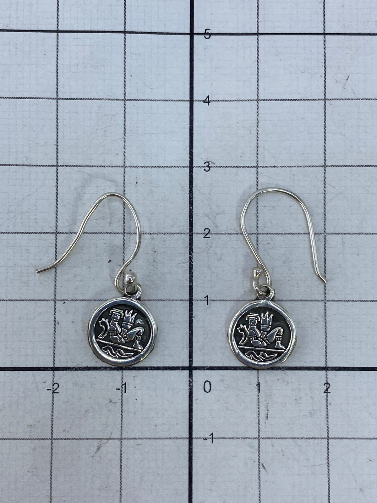 Aretes de plata sobre fondo blanco mostrando el Quinto 925 en el reverso