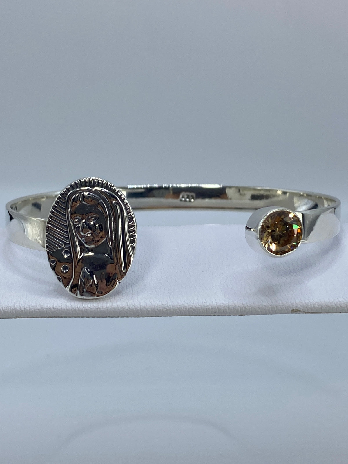 Brazalete de plata rígido con circonia café en la muñeca de una mujer