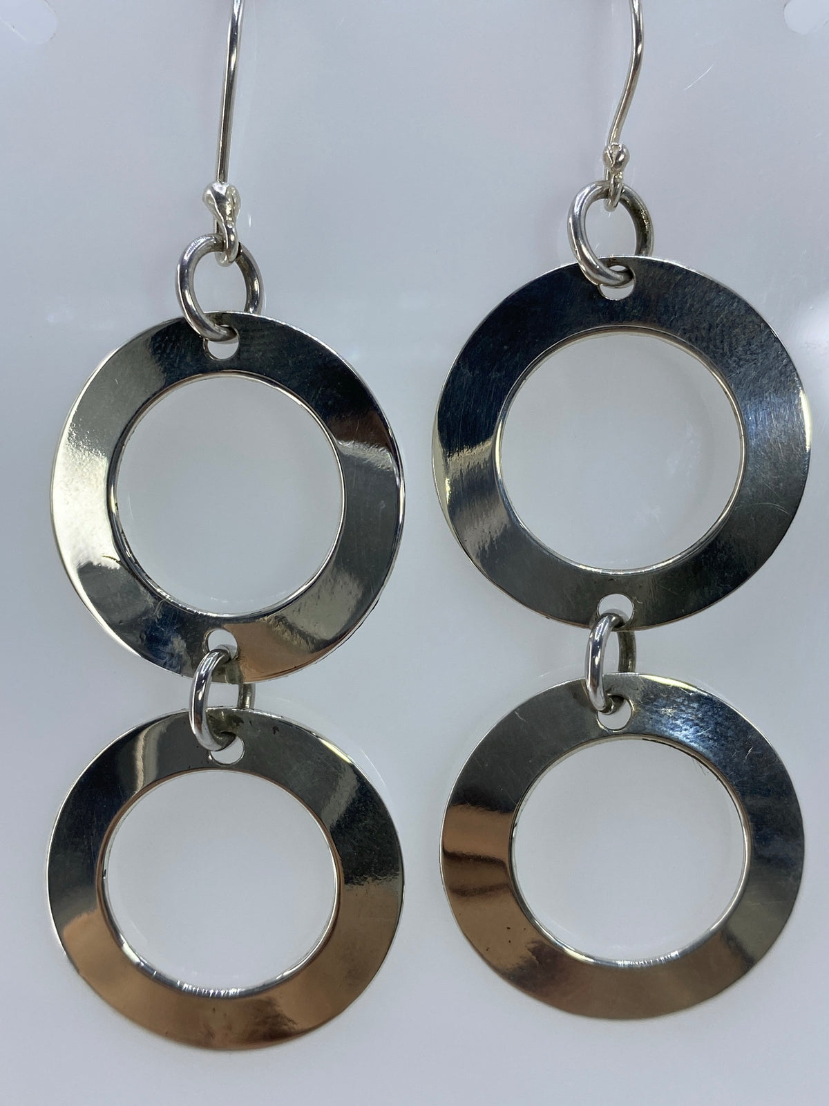 Aretes de plata puestos, luciendo la geometría cortada contra la piel