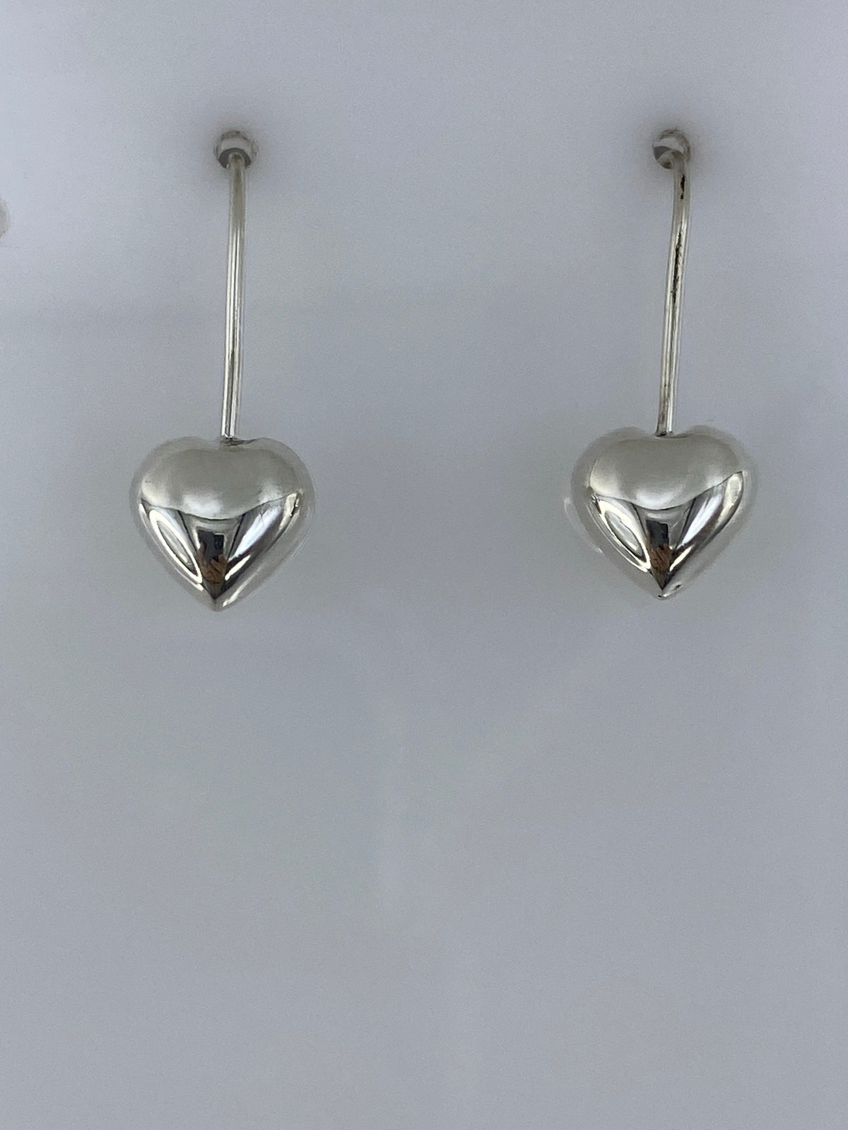 Detalle lateral de un arete de corazón en plata 925, visto de perfil