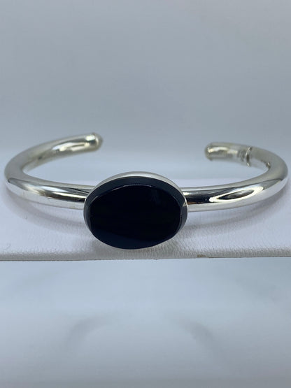 Brazalete de plata puesto en la muñeca mostrando el ónix negro brillante