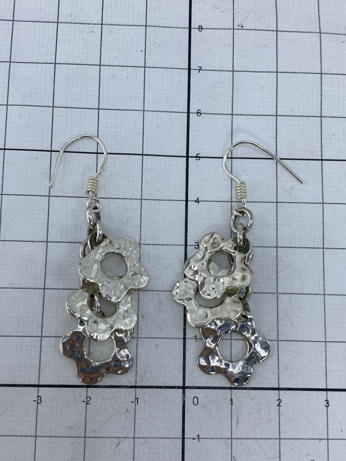 Aretes con gancho de plata sobre fondo neutro mostrando la medida de 5.3 cm