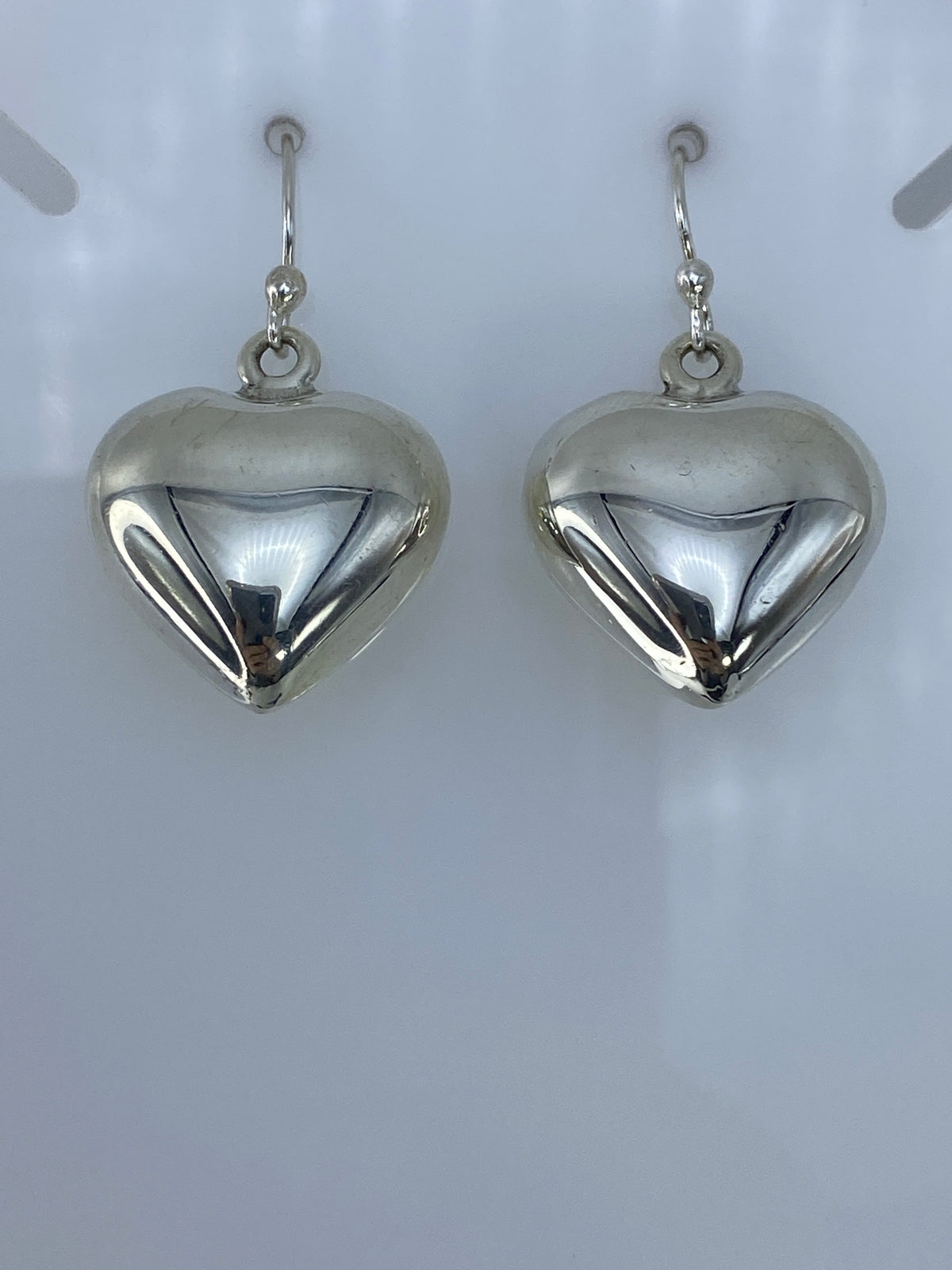 Vista frontal de los aretes corazón pulidos, brillo de plata auténtica