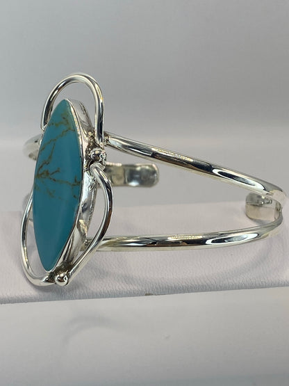 Brazalete de plata abierto mostrando el engaste de turquesa desde el lateral