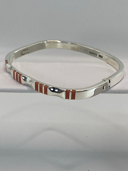 Brazalete de plata puesto en la muñeca, mostrando el ancho de banda y el coral rosa