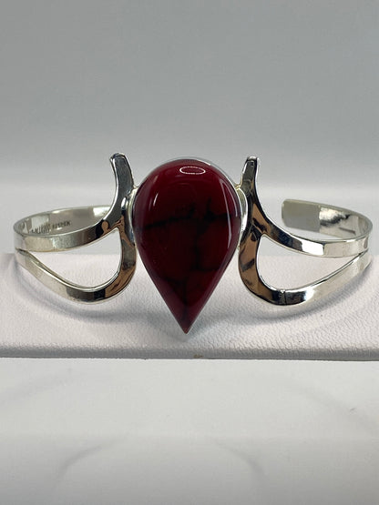 Brazalete de plata rígido con coral rojo engastado, vista frontal sobre fondo blanco