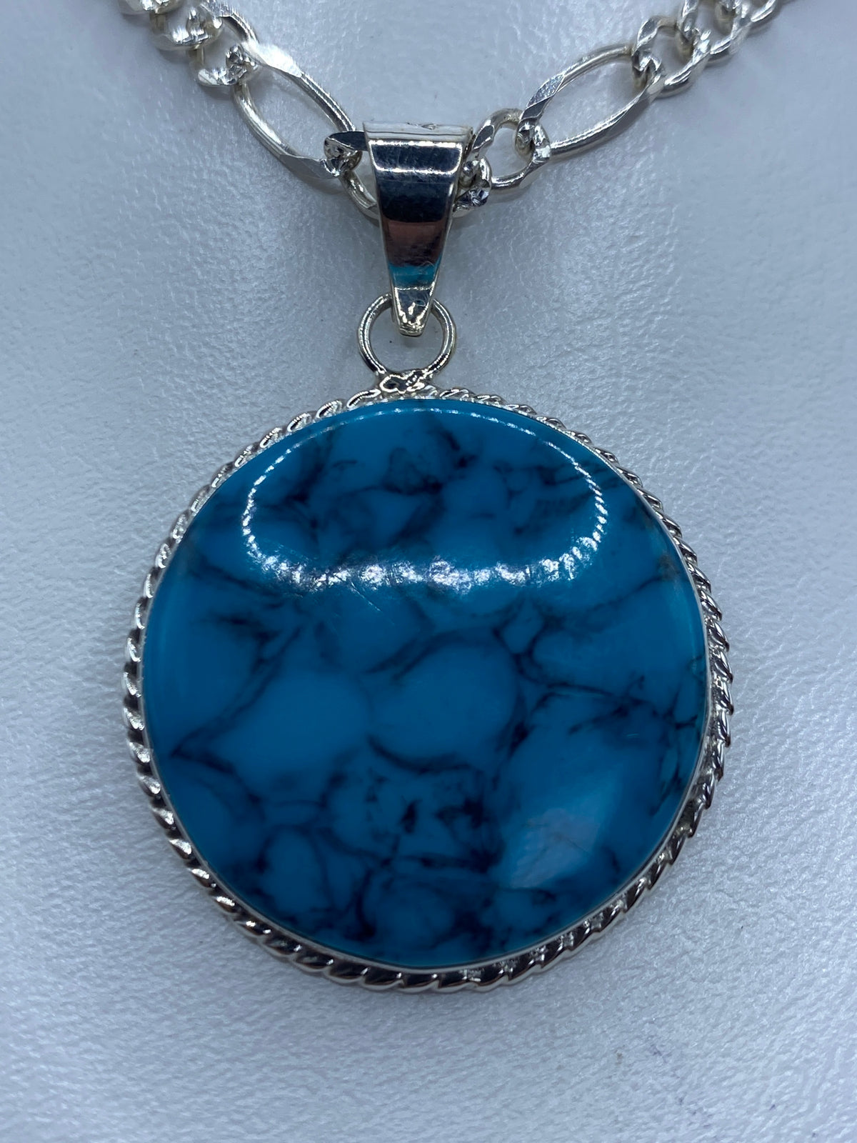 Dije redondo de plata 950 con turquesa azul engastada en marco labrado
