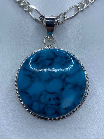 Dije redondo de plata 950 con turquesa azul engastada en marco labrado
