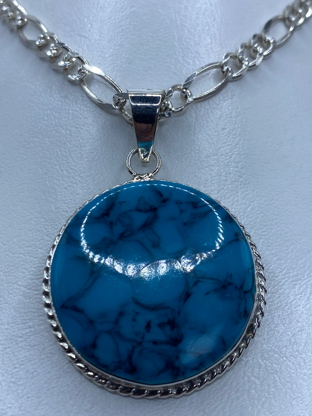 Detalle del engaste de turquesa en plata 950, visto de frente mostrando el color azul profundo