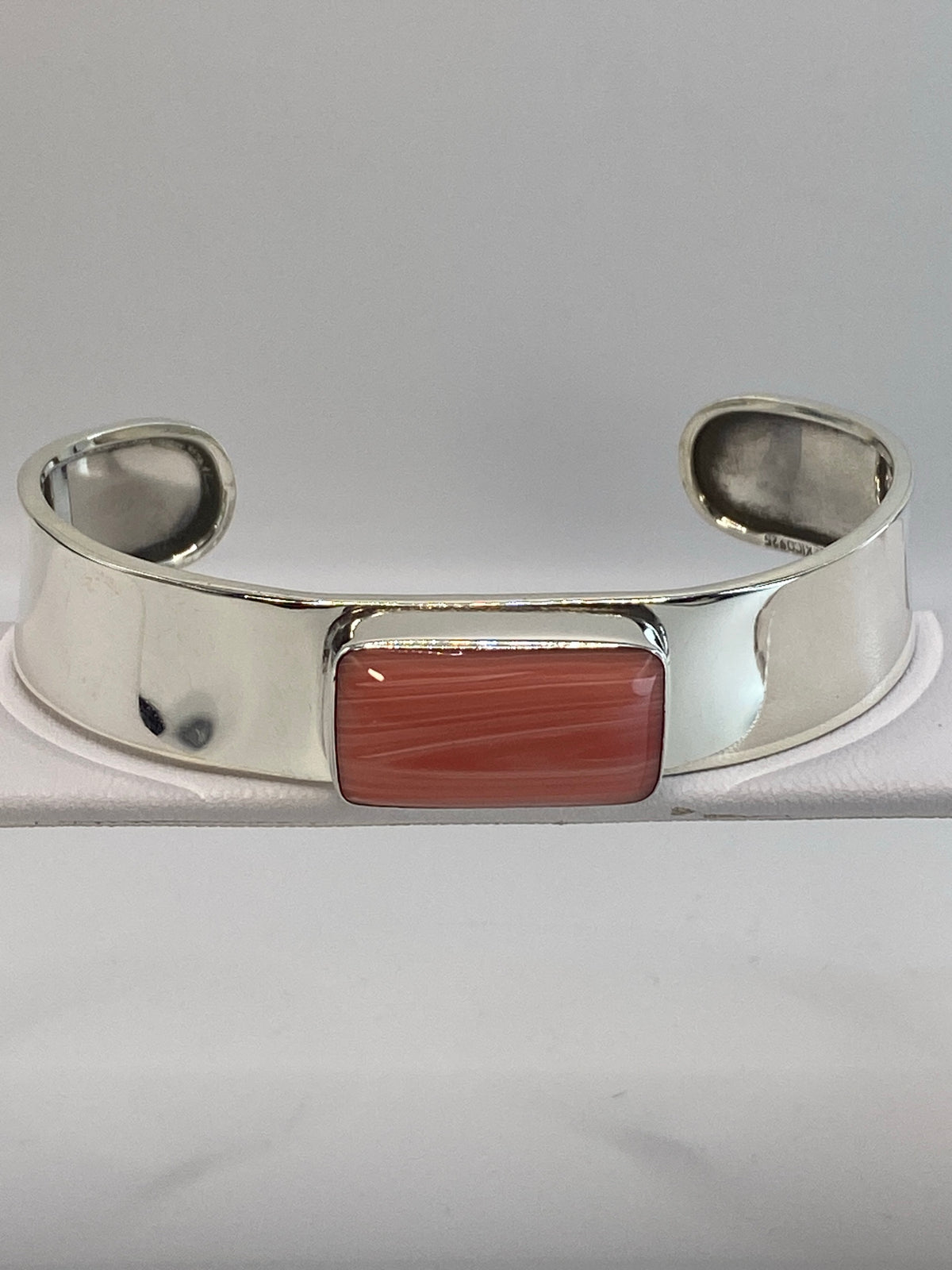 Brazalete de plata rígido con coral roja engastada en el centro, vista frontal
